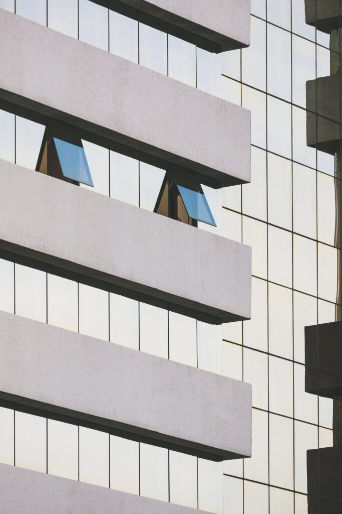 blue glass windows that are opening on modern high glass office building wall in vertical frame